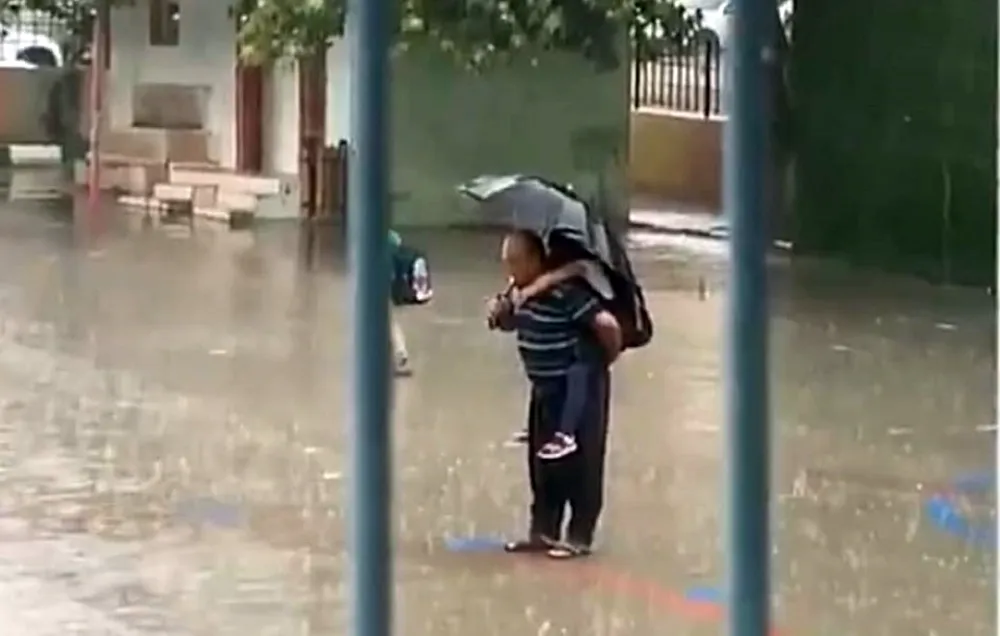 Dede torununu sırtına alarak yağmur altında İstiklal Marşı okudu